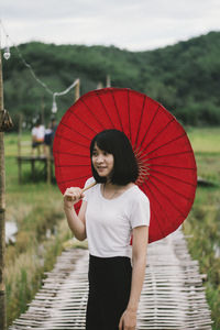 Full length of woman holding red umbrella