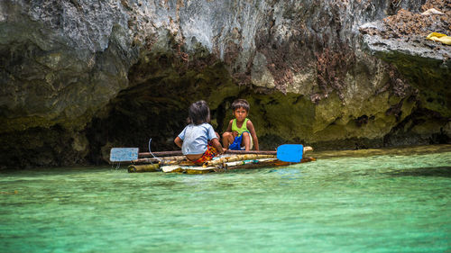 People sitting on rock in water