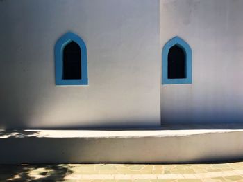 Simple white stone walls with two blue window frames in mystic light 