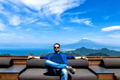 Portrait of man sitting on sofa against blue sky