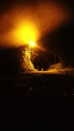 Illuminated field against sky at night