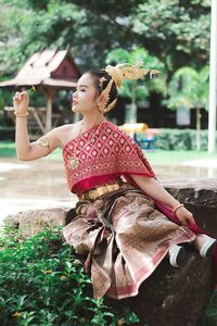 Young woman with umbrella while sitting on tree