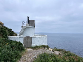 Lighthouse by sea against sky