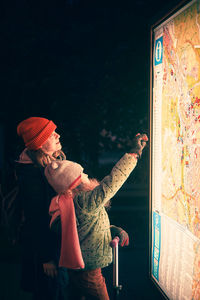 Mother and child waring in warm clothing looking for the way on a city map.