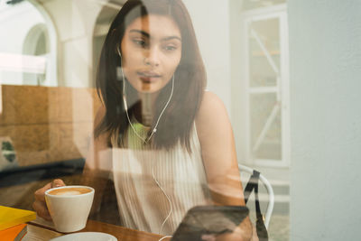 Young woman enjoys music during coffee break in cafe