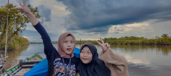 Portrait of woman by lake against sky