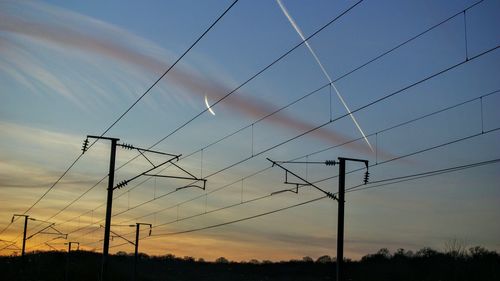 Low angle view of electricity pylon against cloudy sky