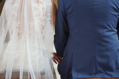 Midsection of bride and room sitting in wedding ceremony