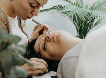 Portrait of a girl cosmetologist extending eyelashes to a woman.