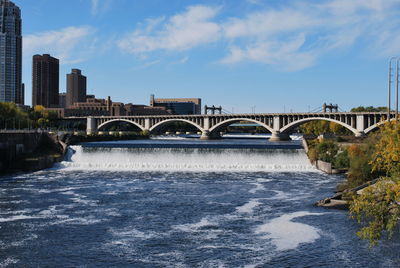 Arch bridge over river in city against sky