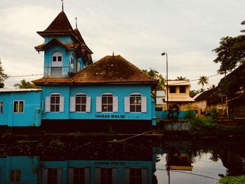 Building by canal against sky in city