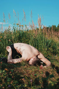 Shirtless man lying on grassy field