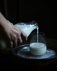Cropped hand of person pouring drink on table