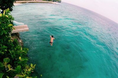 Shirtless man in mid-air over sea