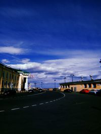 Road by buildings against sky in city