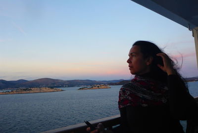 Woman looking away against sky during sunset