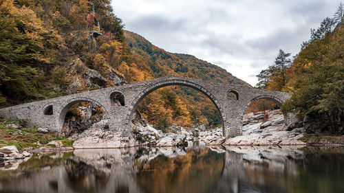 Arch bridge over river against sky