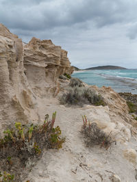 Rock formation on beach against sky