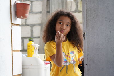 Portrait of woman standing against yellow wall