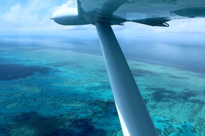 Close-up of airplane wing over sea against sky