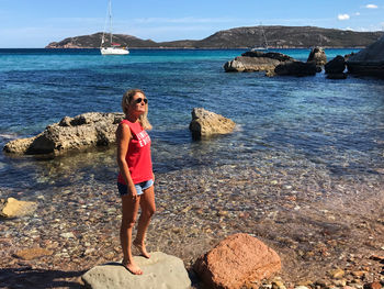 Full length of woman standing on rock at beach