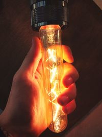 Close-up of hand holding illuminated light bulb