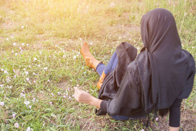 Woman wearing headscarf sitting on field 