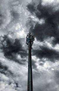 Low angle view of communications tower against cloudy sky