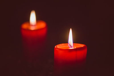 Close-up of candles burning against black background