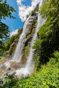 Scenic view of waterfall in forest against sky