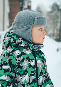 Rear view of boy looking at snow during winter