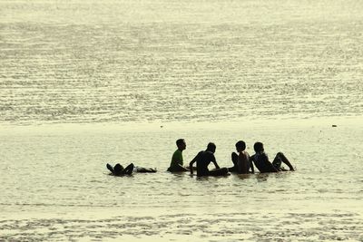Silhouette people sitting on beach