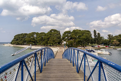 Footbridge over sea against sky