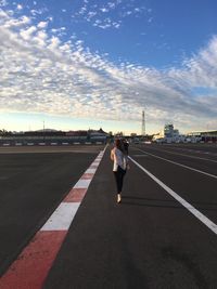 Rear view of man standing on road against sky