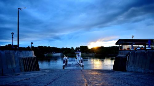 People on water against sky at sunset