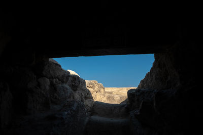 Rock formation against sky seen through cave