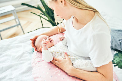 Midsection of mother and baby girl on bed