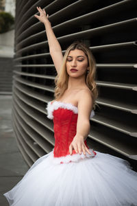 Portrait of young woman standing against wall