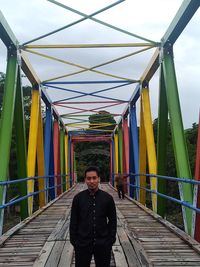 Portrait of man standing on bridge against sky