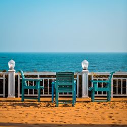 Deck chairs on beach against clear sky