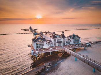 Drone view of stilt houses on pier over sea against sky during suset