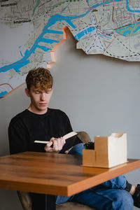 A man in a cafe sits at a table reading a book, enthusiastically looks at a textbook, in a black 