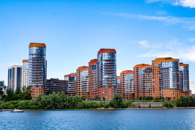 Buildings by river against sky