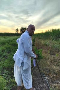 Man standing on field against sky during sunset