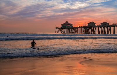 Silhouette people at beach against sky during sunset