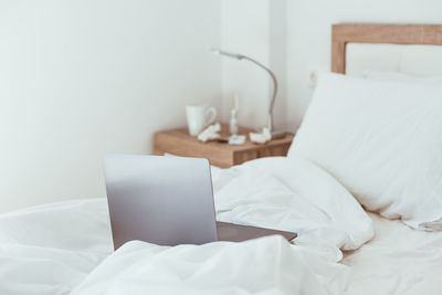 Midsection of man using laptop on bed at home