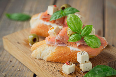 Bruschetta with smoked salmon, cream cheese, olives and arugula on wooden plate