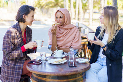 Woman with friends having breakfast at sidewalk cafe