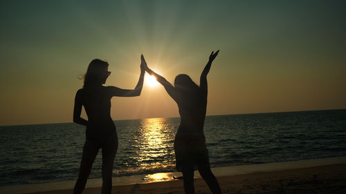 Silhouette people at beach against sky during sunset