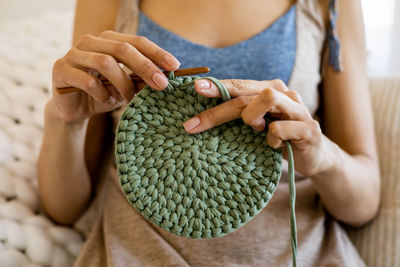 Midsection of woman knitting at home